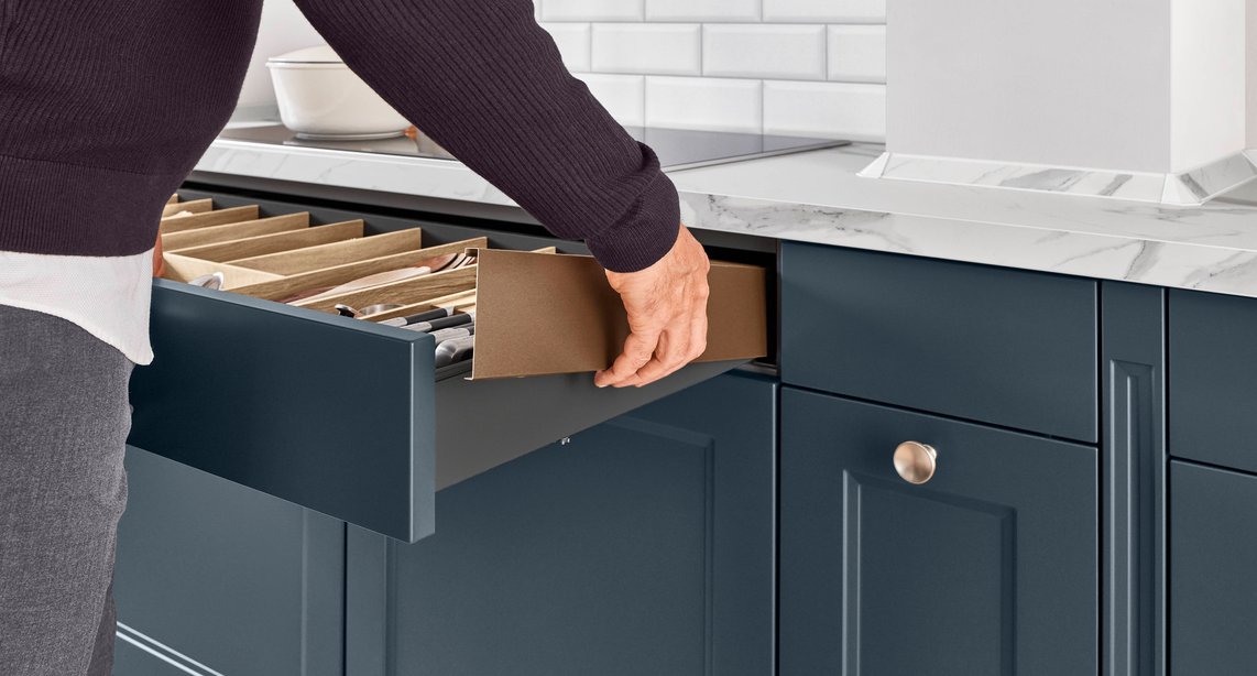 Order by design — the Cascada's deep drawer opens to reveal a fully organised knife and cutlery divider system, built into navy cabinetry with a marble worktop above.