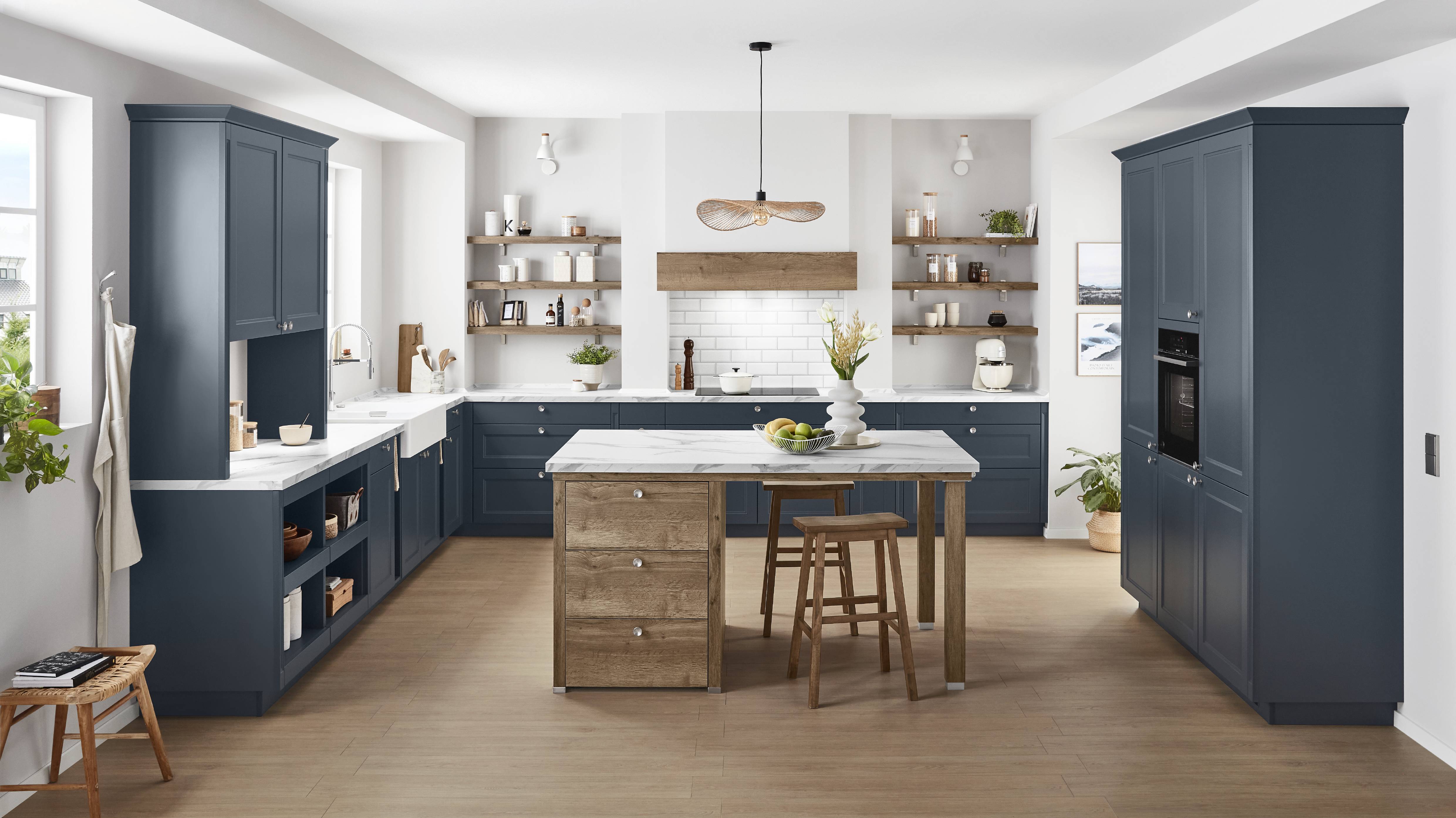 Built to last, designed to love — the Noblessa navy shaker kitchen pairs frame-and-panel cabinetry with a rustic oak island, marble worktops, and open shelving that make every benefit of German craftsmanship visible.