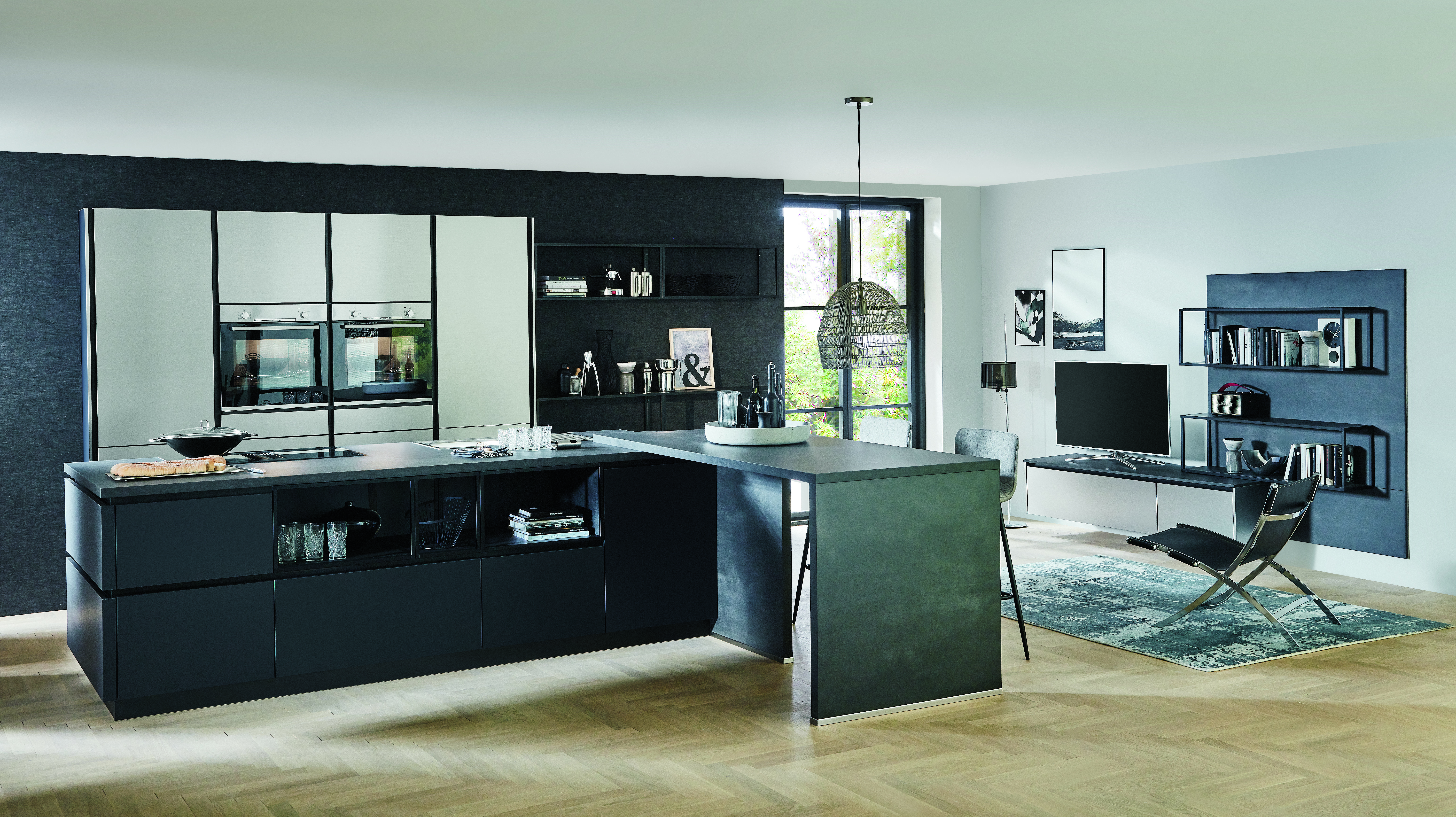 The upgrade that changes everything — a full matte black kitchen with a cantilevered island extension, framed appliance wall, and open living zone shows what a high-end remodel truly looks like.